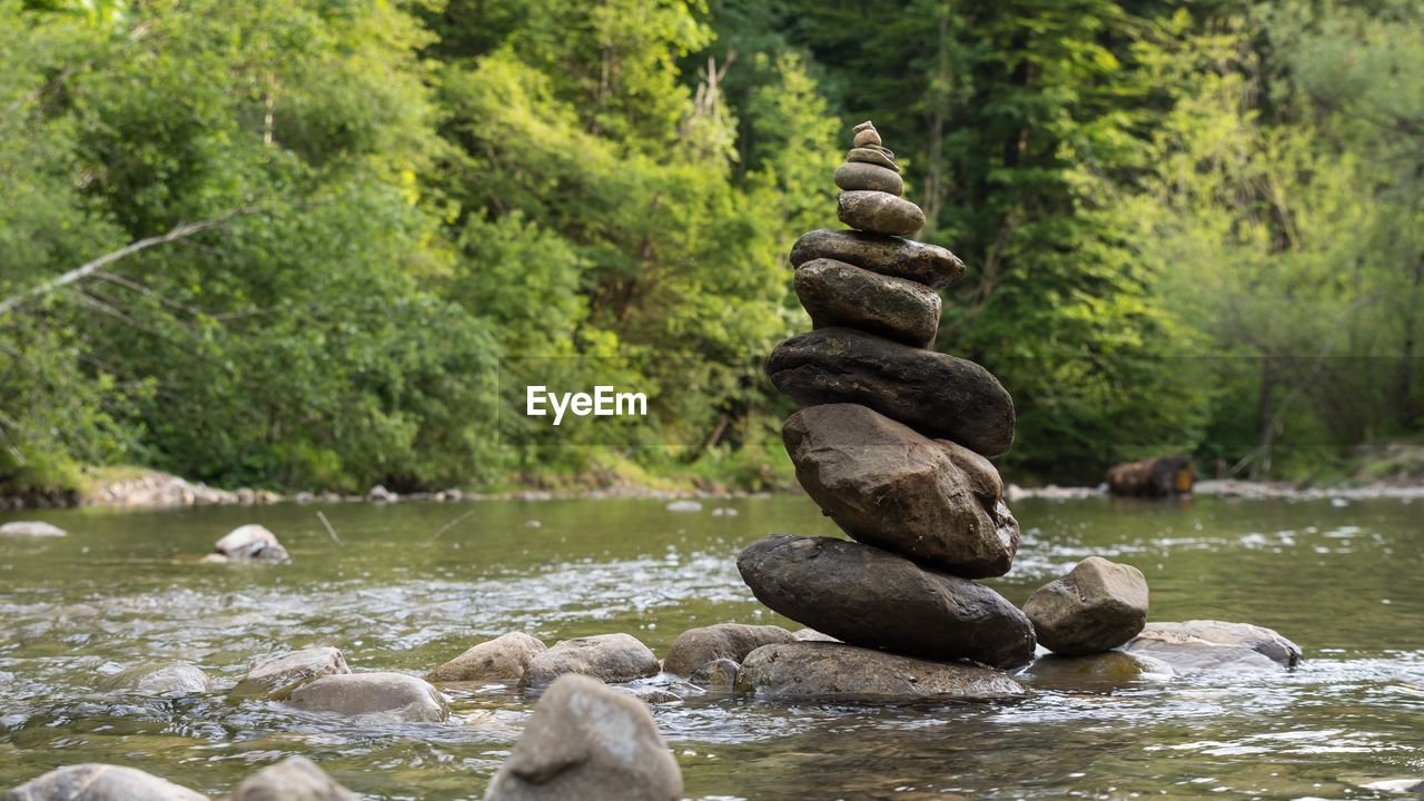 Stack of stones amidst river at forest