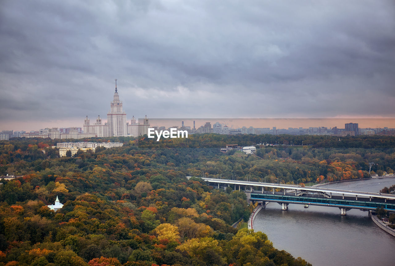 View of trees in city against cloudy sky during sunset