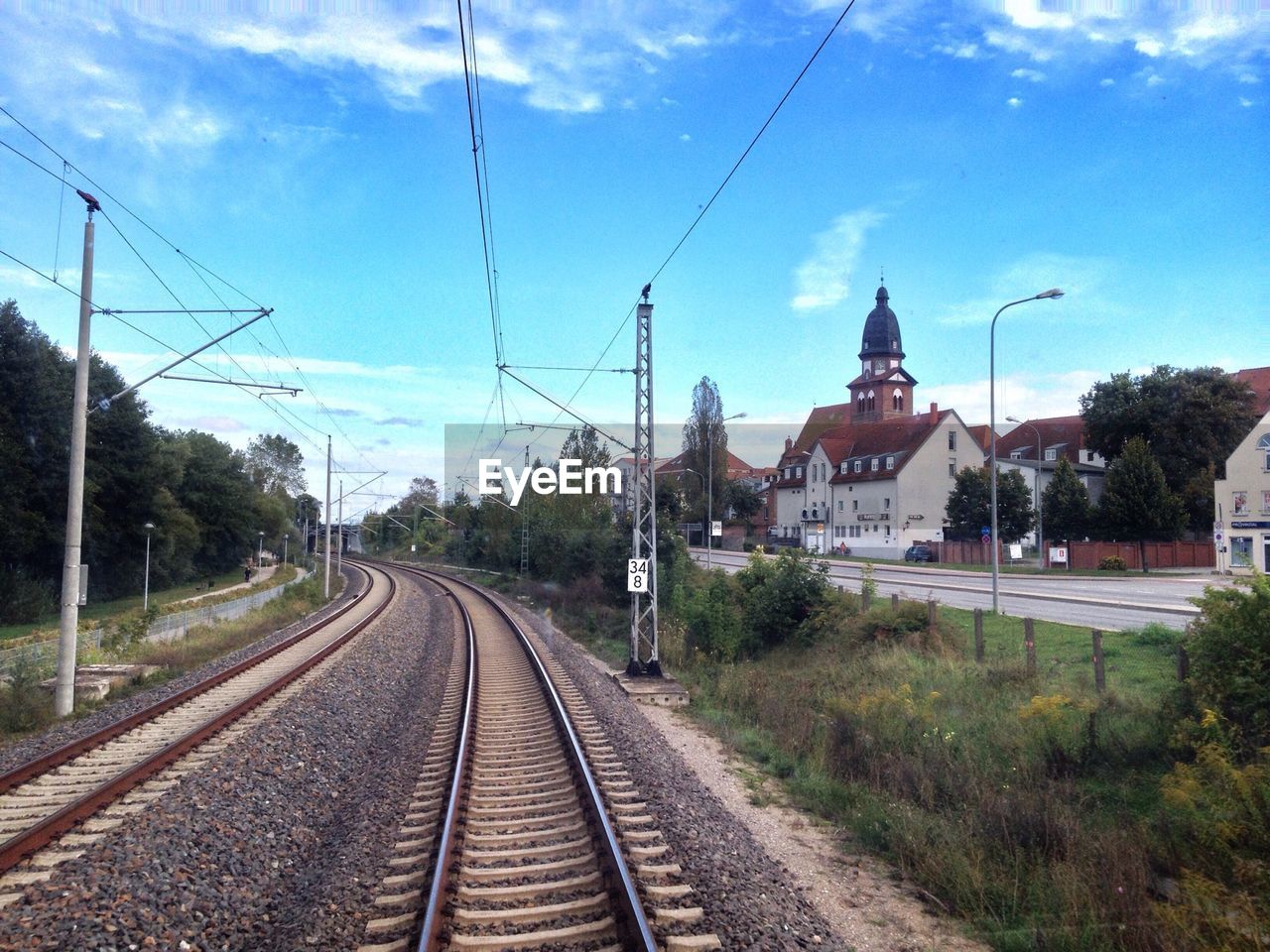 Railroad track by houses against sky