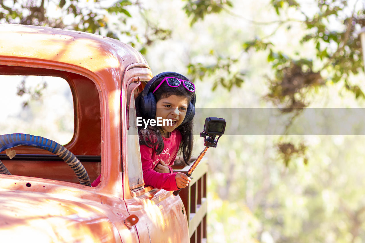 Smiling girl holding camera in car 