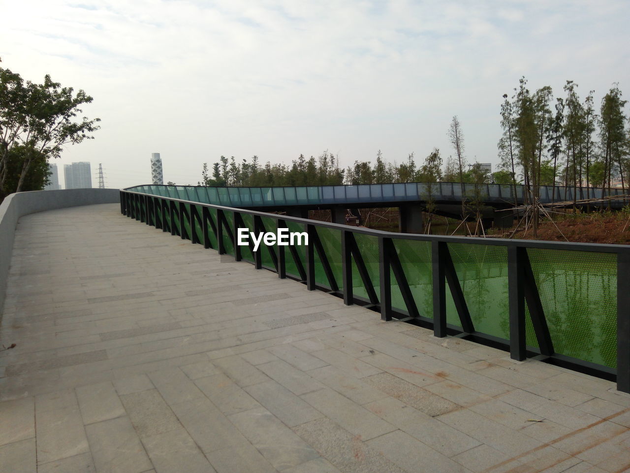 RAILING BY TREES AGAINST SKY