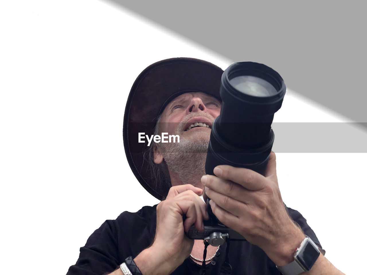 Low angle view of man wearing hat holding camera