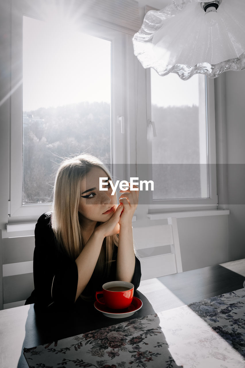 Young woman sitting on table at home