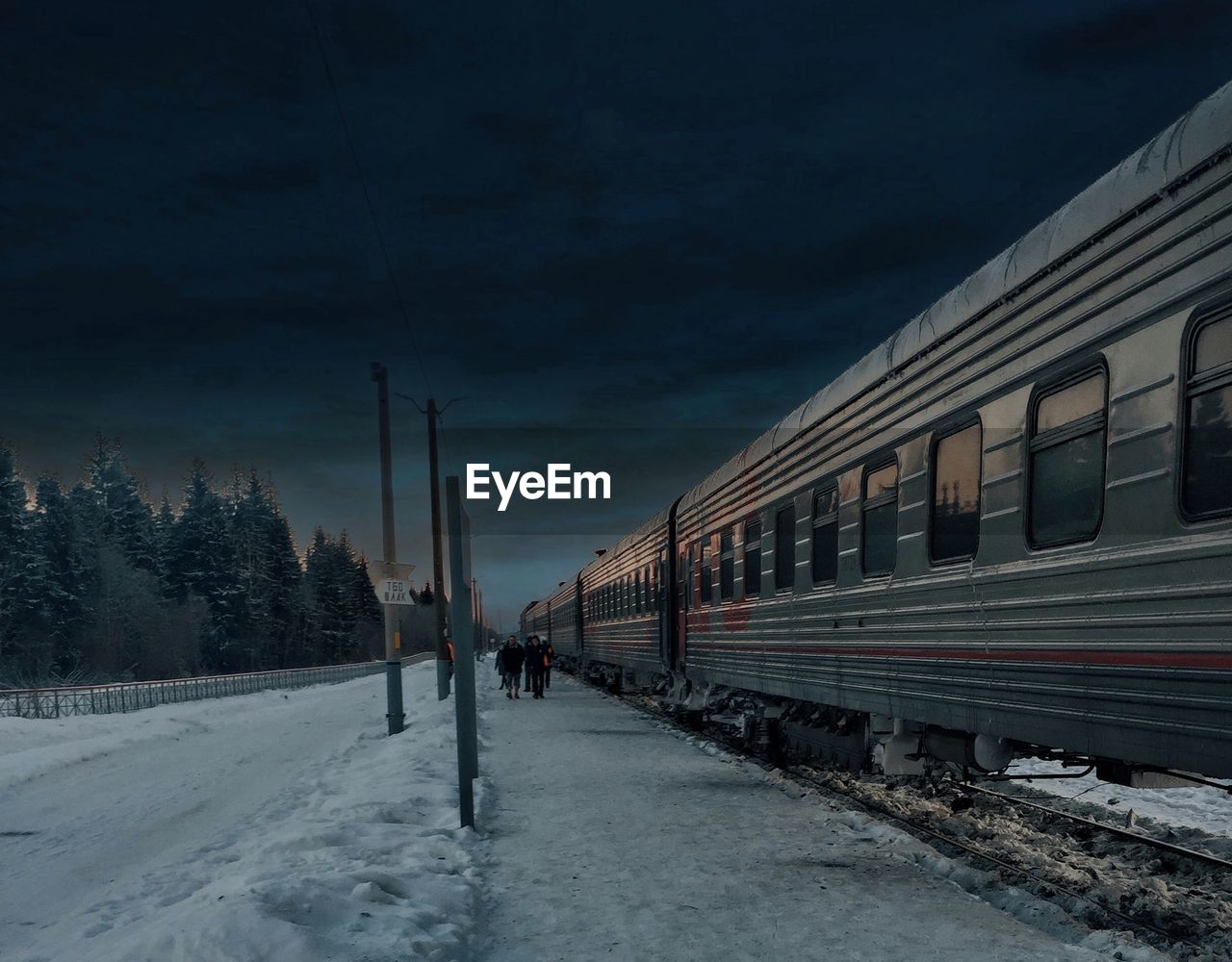 TRAIN ON SNOW COVERED RAILROAD TRACKS AGAINST SKY