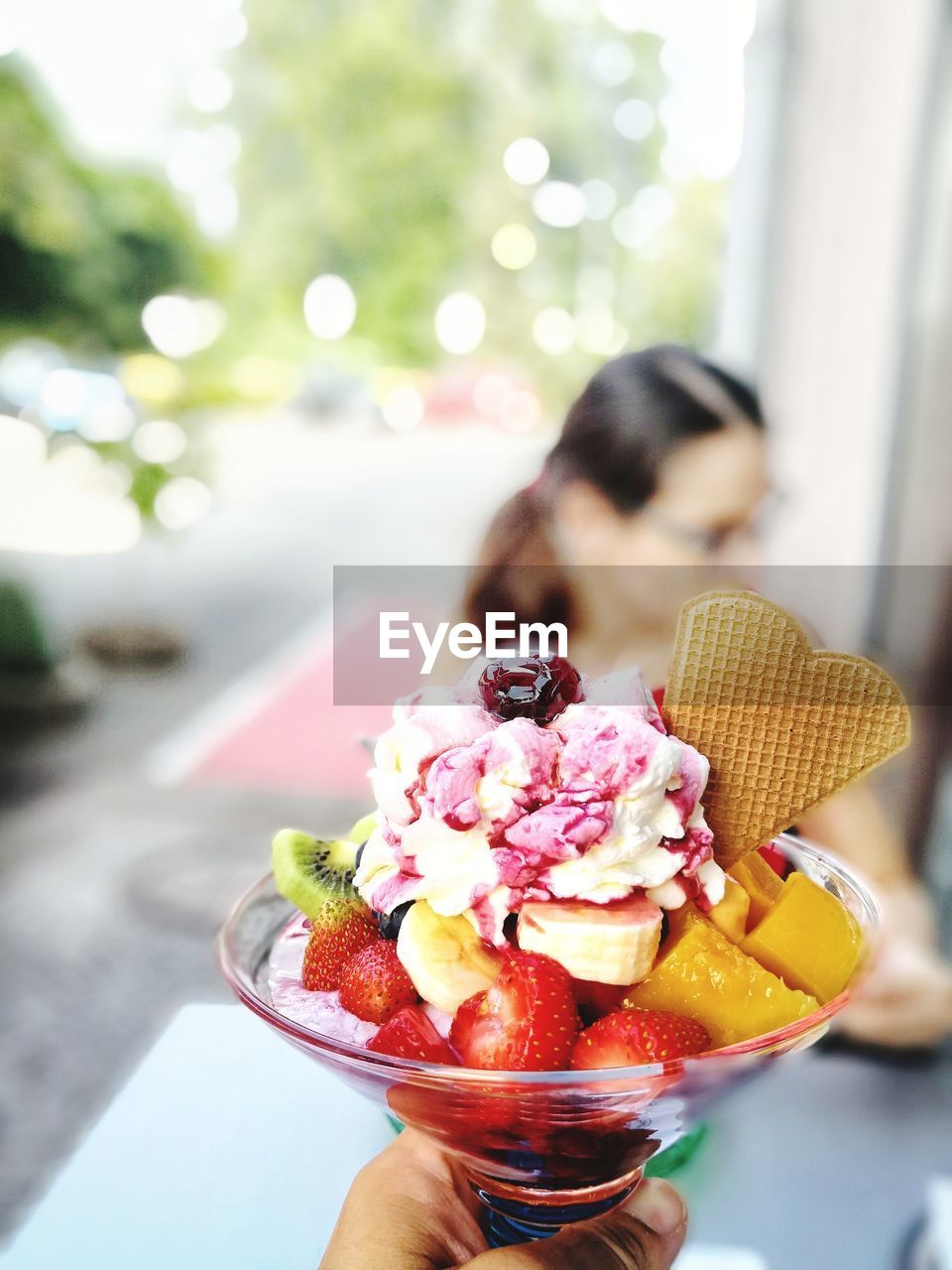 Cropped image of person holding ice cream sundae outdoors