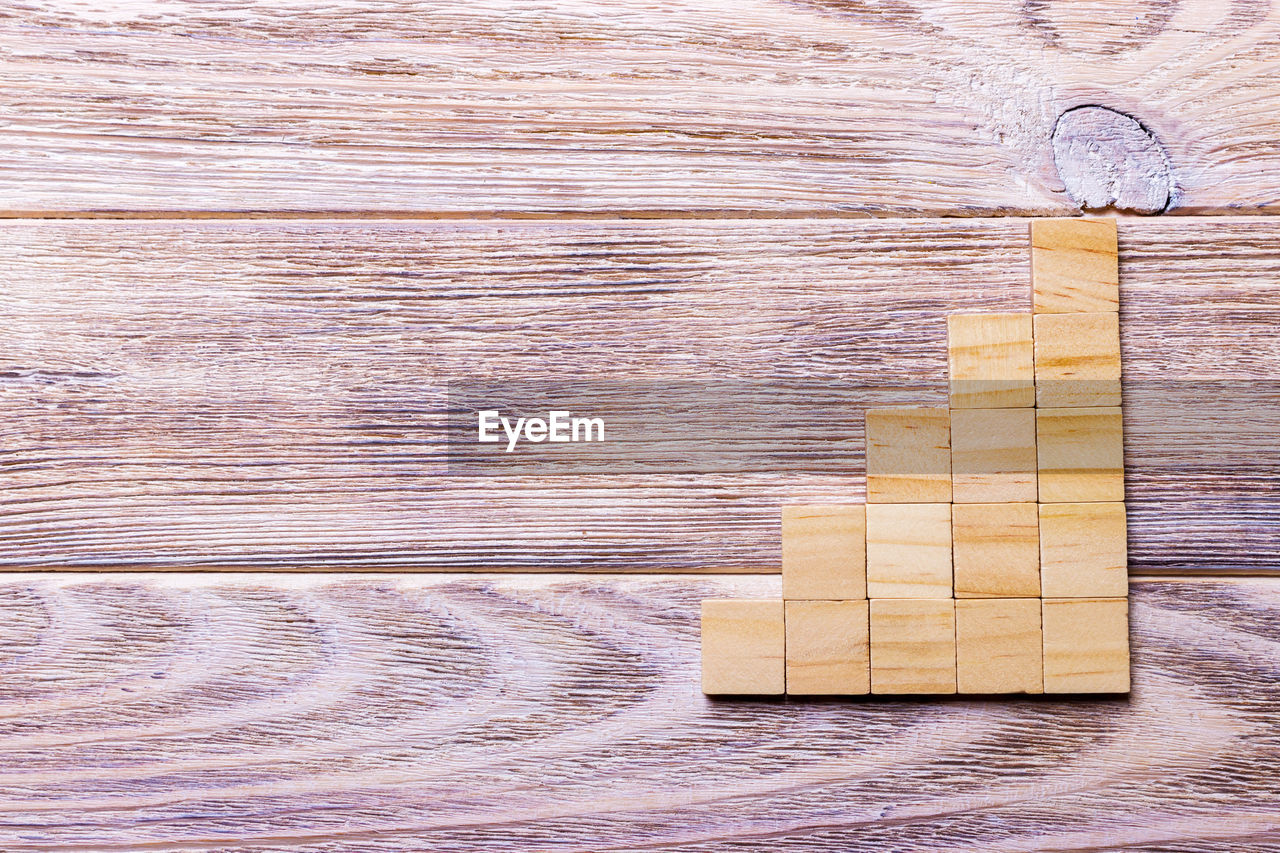 A wooden blocks cube over black wooden textured background with copy space 