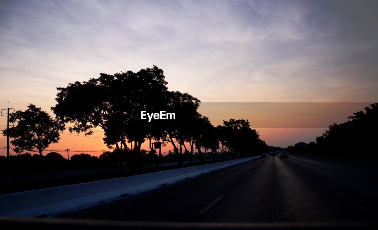 EMPTY ROAD WITH TREES IN BACKGROUND