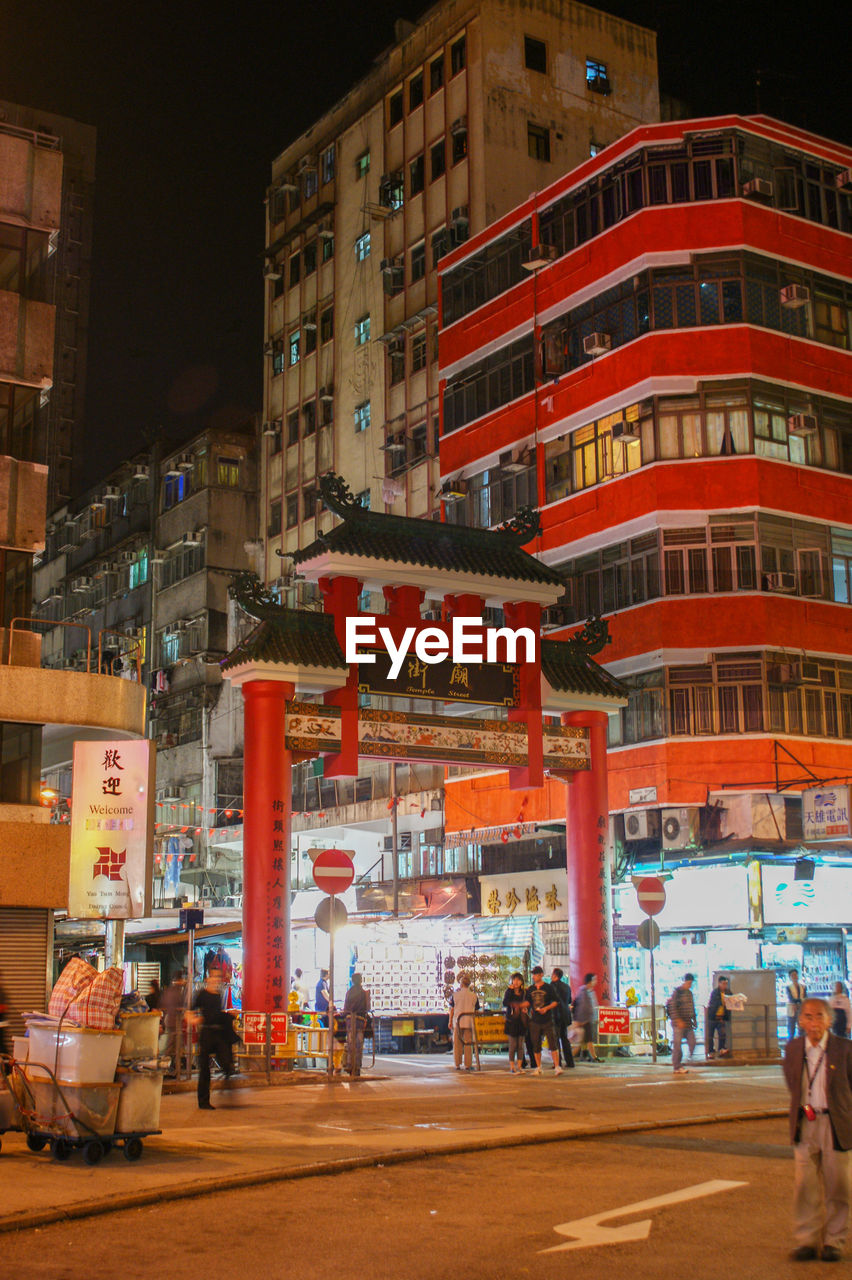 People on street amidst buildings in city at night