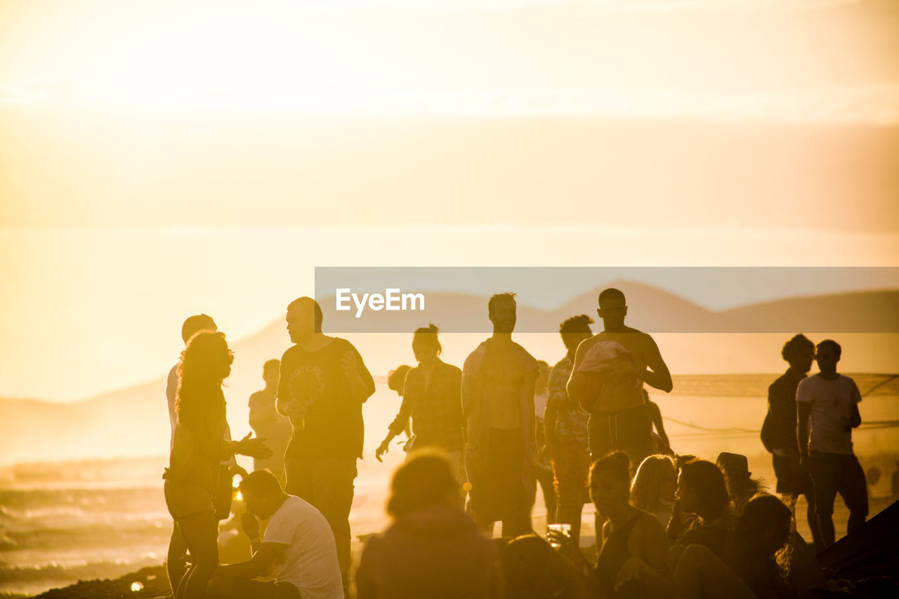 PEOPLE STANDING IN SEA AGAINST CLEAR SKY