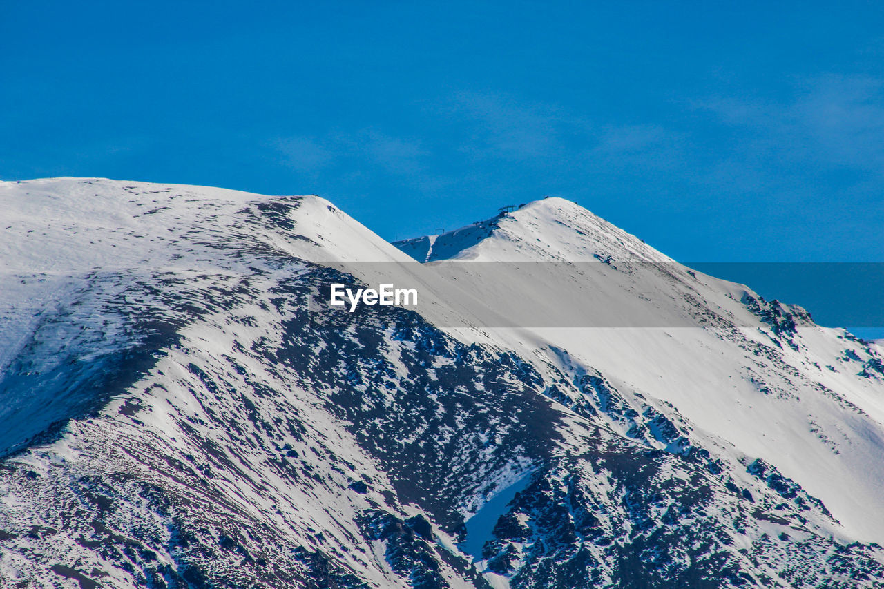 Scenic view of snowcapped mountains against blue sky