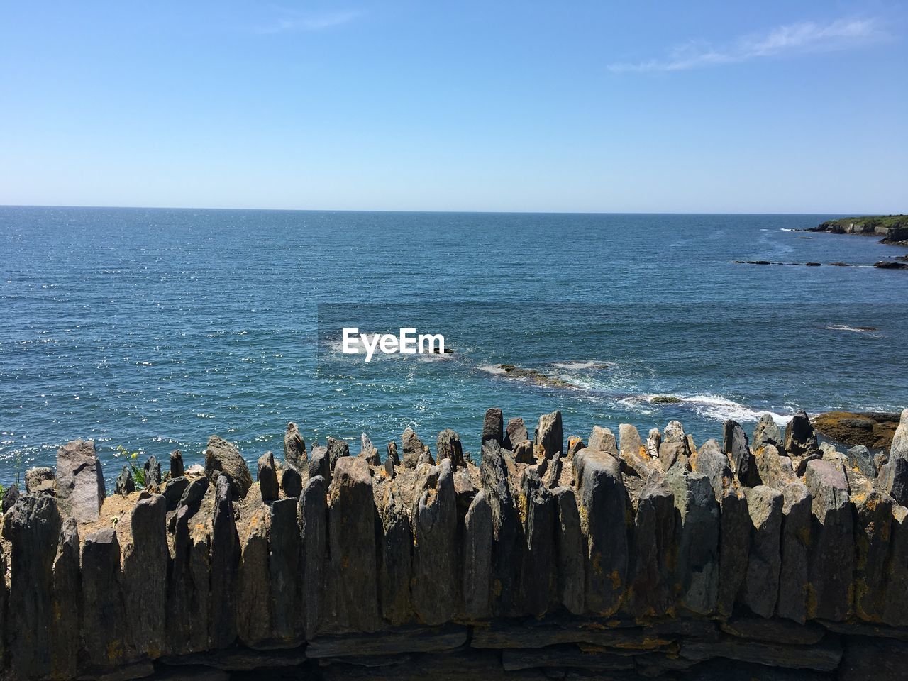 Scenic view of sea in front of rocks on sunny day