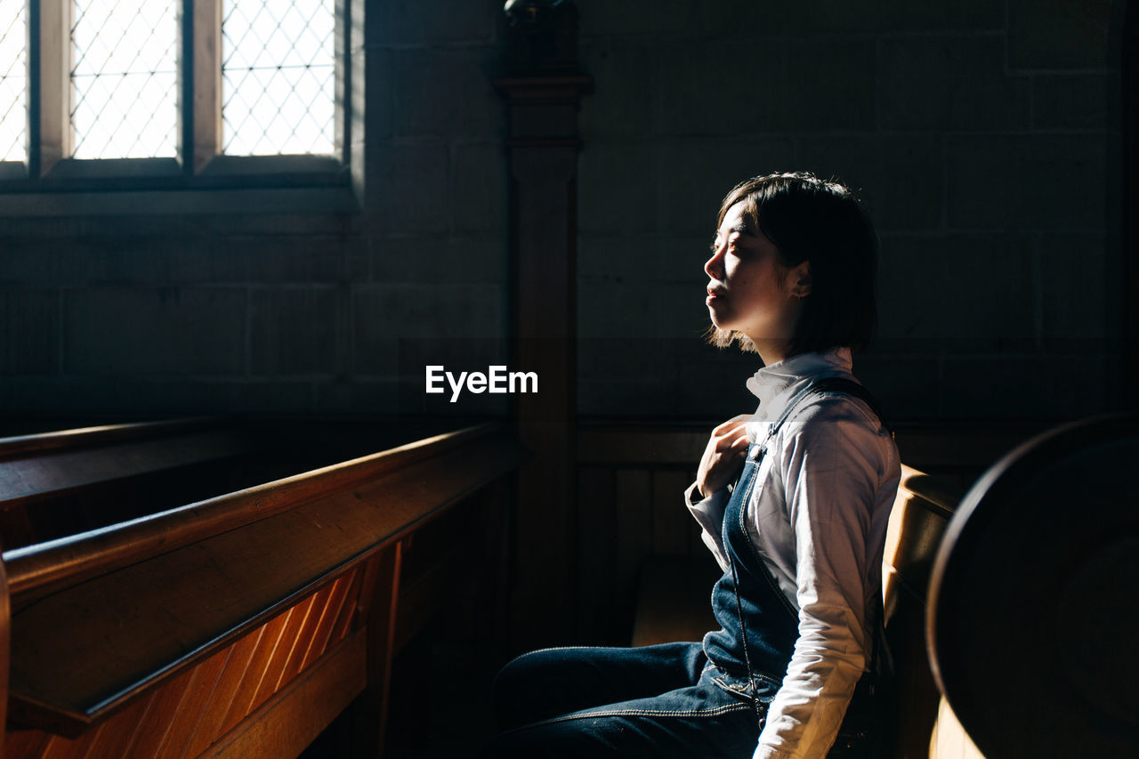 Side view of woman looking away while sitting in church