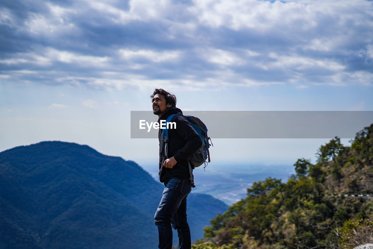 Man with backpack standing on mountain against sky