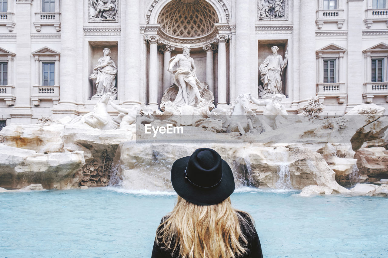 Rear view of woman standing against trevi fountain