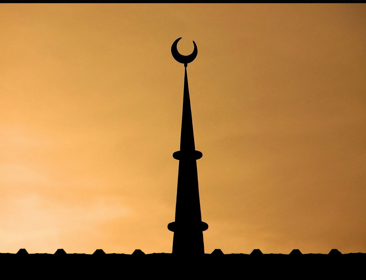 Silhouette minaret of mosque against sky during sunset