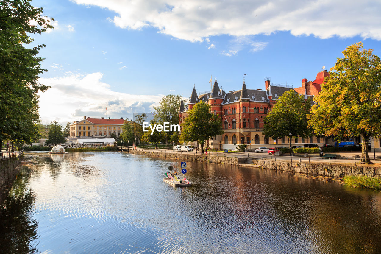 Buildings by river against sky in city