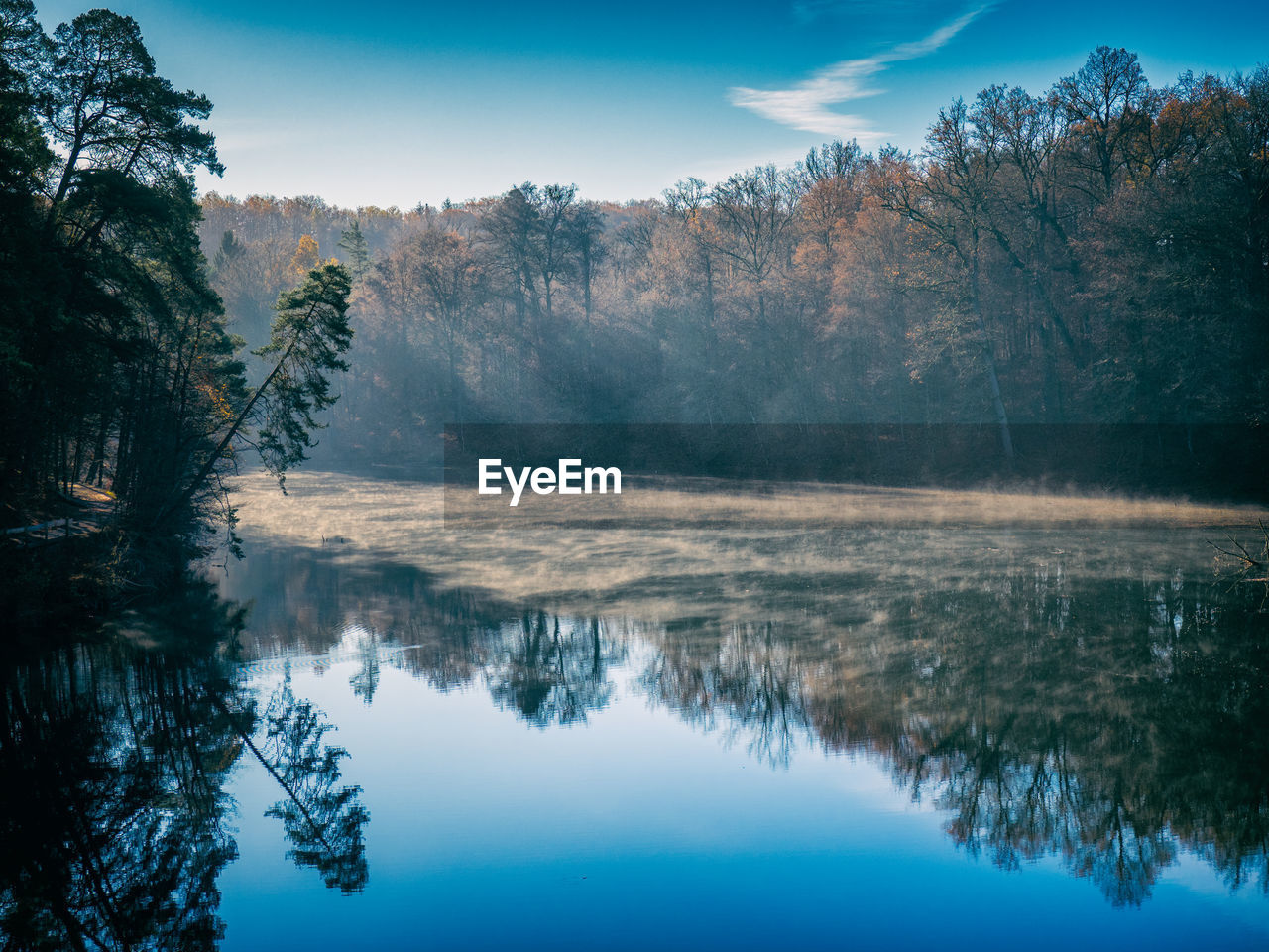 Lonely lake in the morning light with mist over the reflecting water