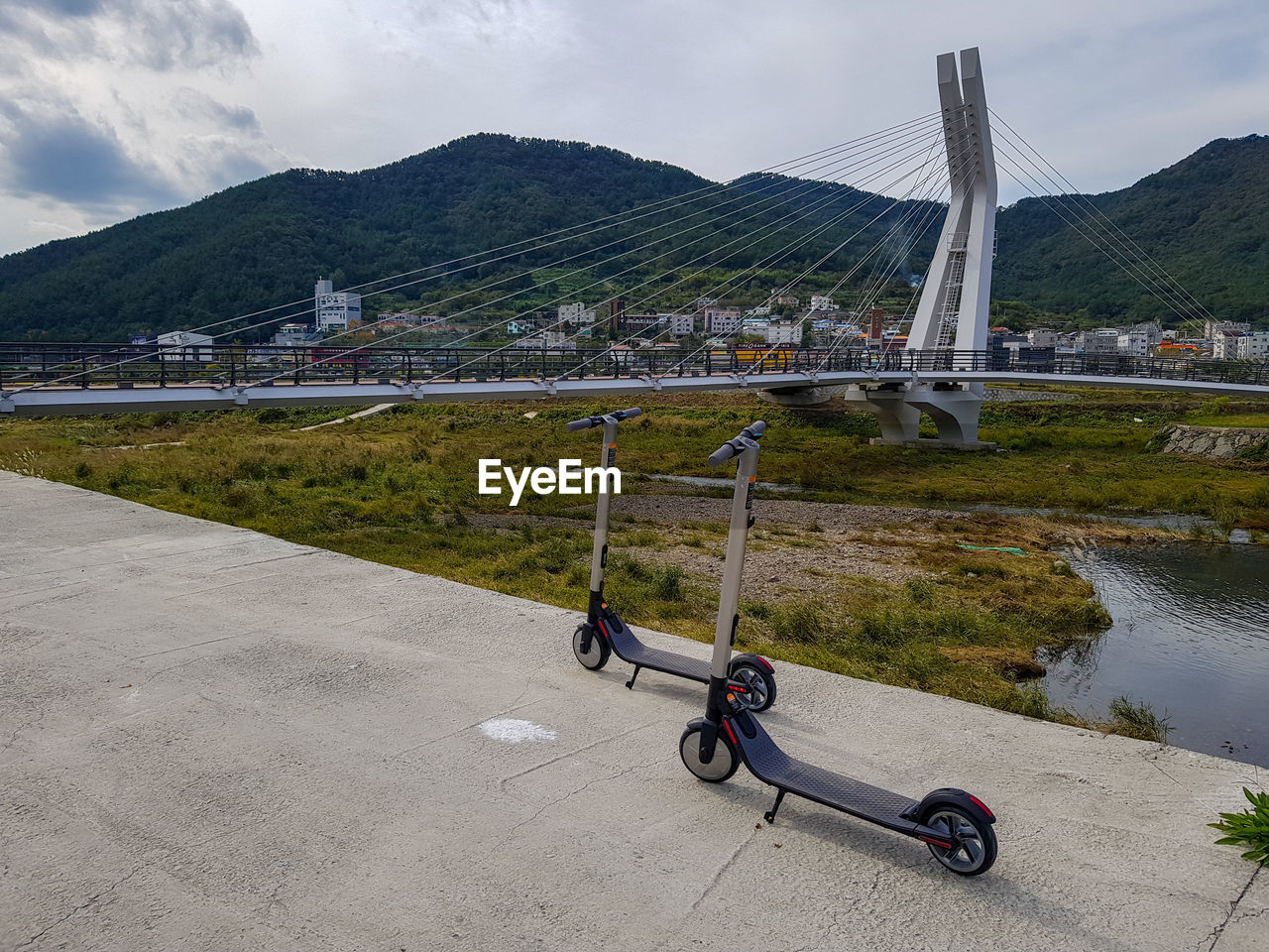 BICYCLE ON BRIDGE OVER RIVER AGAINST MOUNTAIN