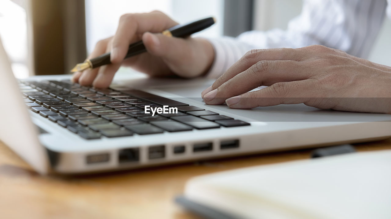 Cropped hands of woman using laptop on table