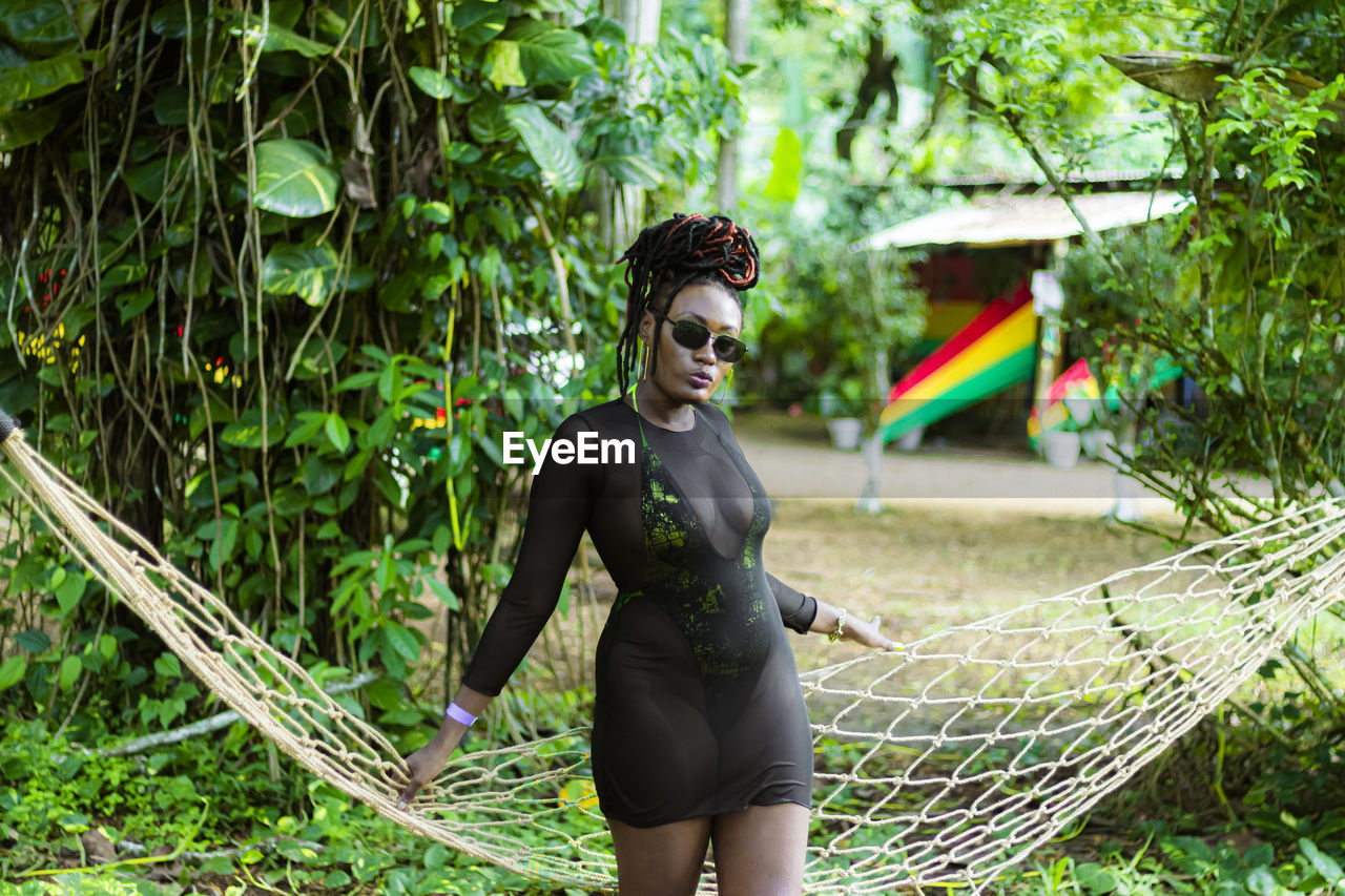 Portrait of young woman standing against trees