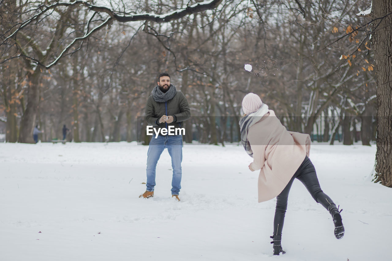 Happy couple playing on snow covered land during winter