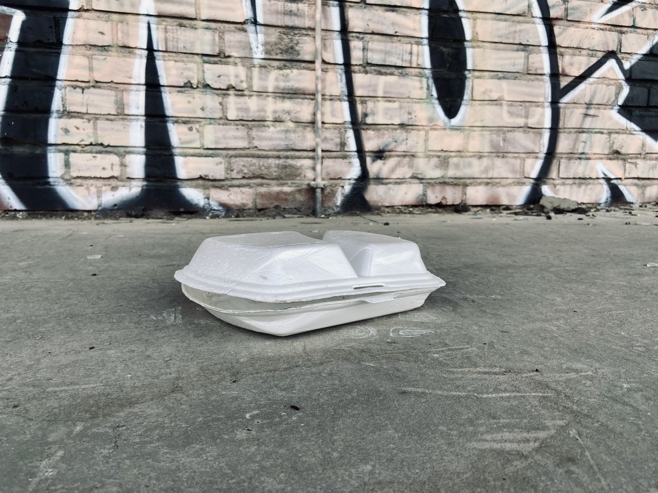 GARBAGE ON SIDEWALK AGAINST WALL IN CITY