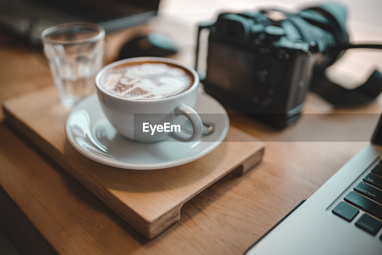 CLOSE-UP OF COFFEE CUP AND WINE ON TABLE