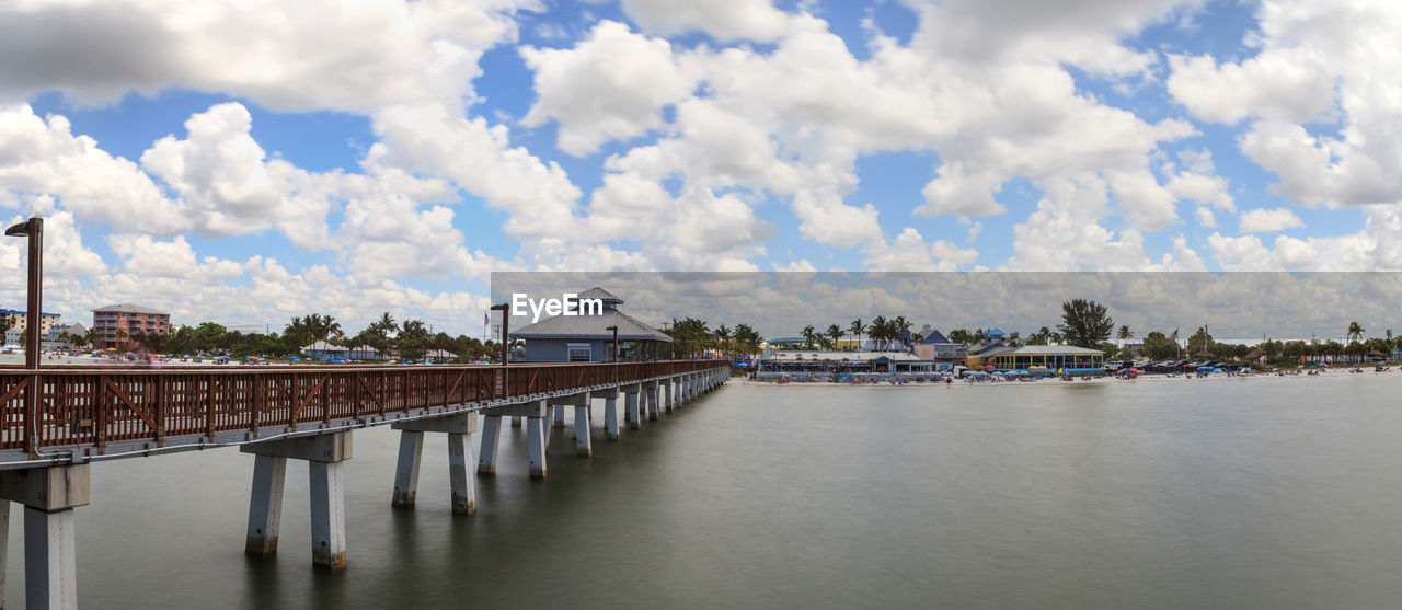 BRIDGE OVER RIVER AMIDST BUILDINGS AGAINST SKY