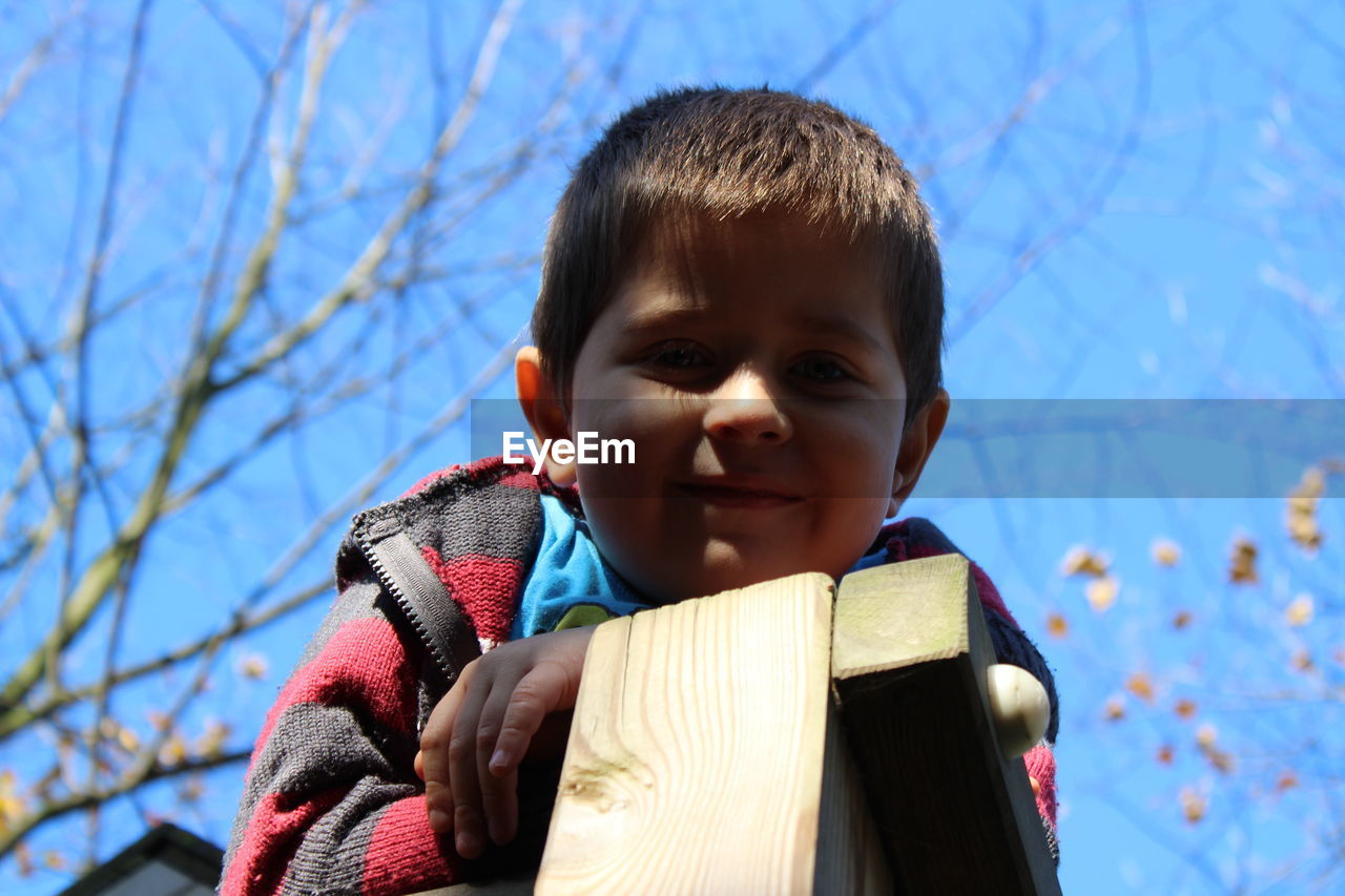 Low angle portrait of smiling boy against sky