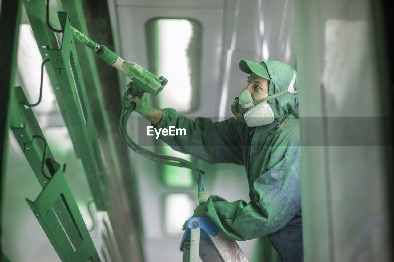 Painters spraying steel components in spray booth of a factory