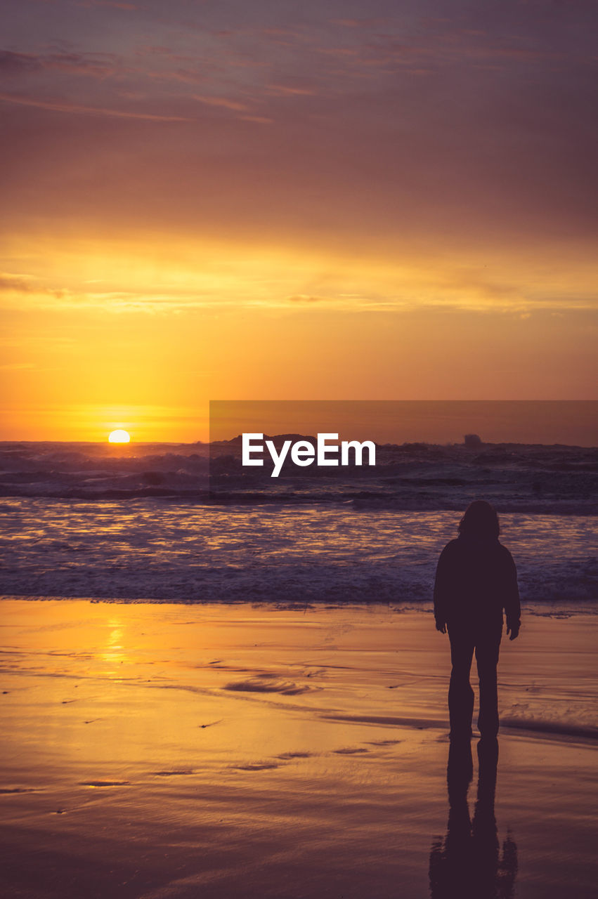 Silhouette man standing at beach during sunset