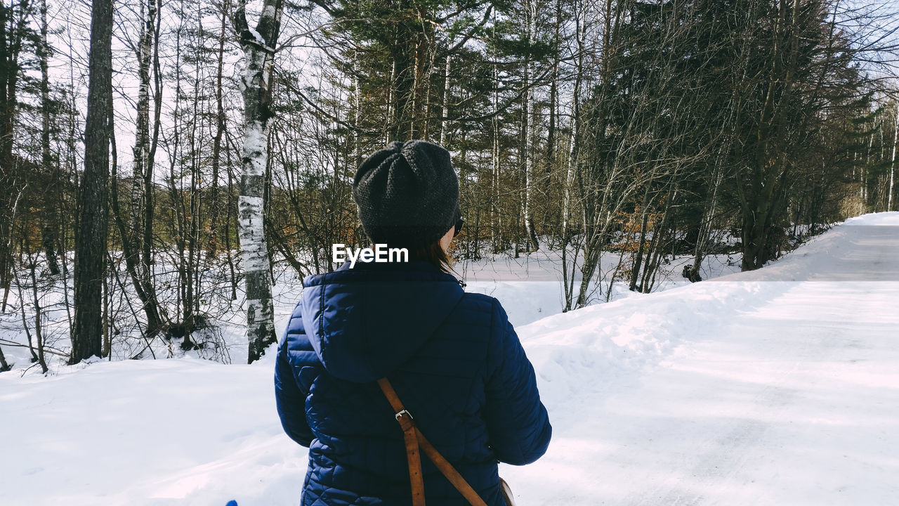 Rear view of woman standing on snow covered land