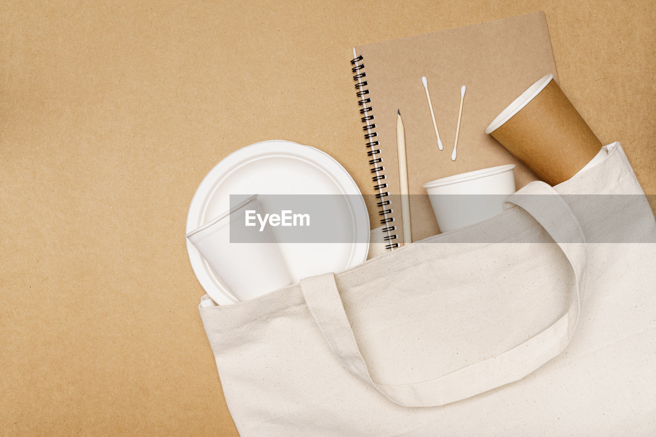 Eco friendly concept, notebook with pencil and food container in eco bag on wooden background.