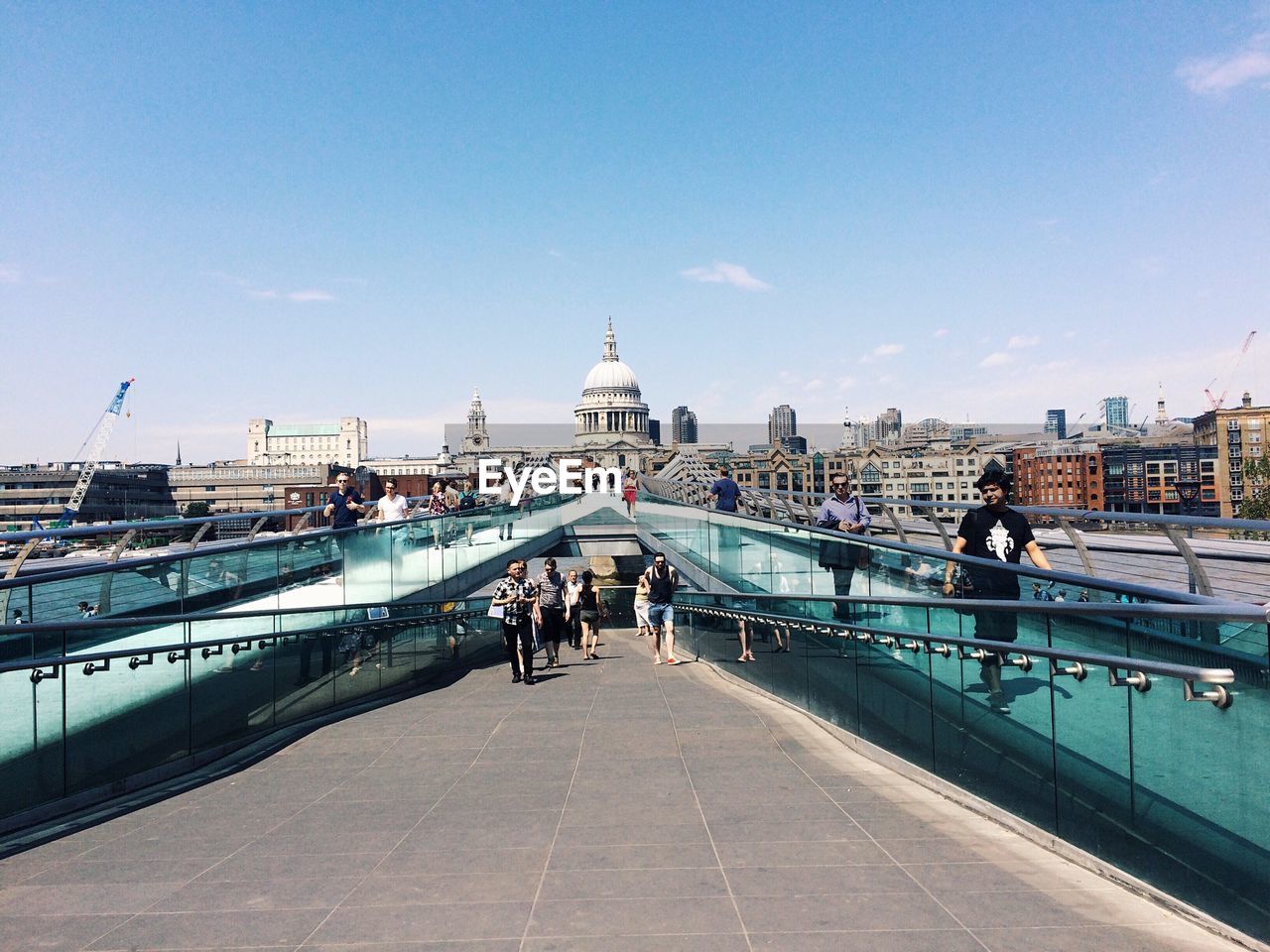 People on london millennium footbridge in city against sky