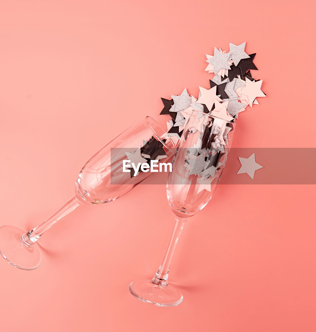 Holidays concept. star shaped confetti pouring out of the glass on pink background flat lay top view