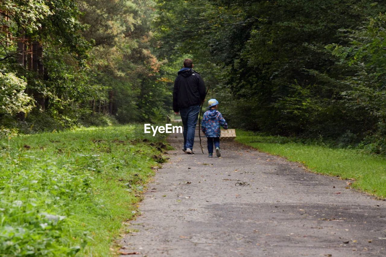 Rear view of father and son walking on footpath