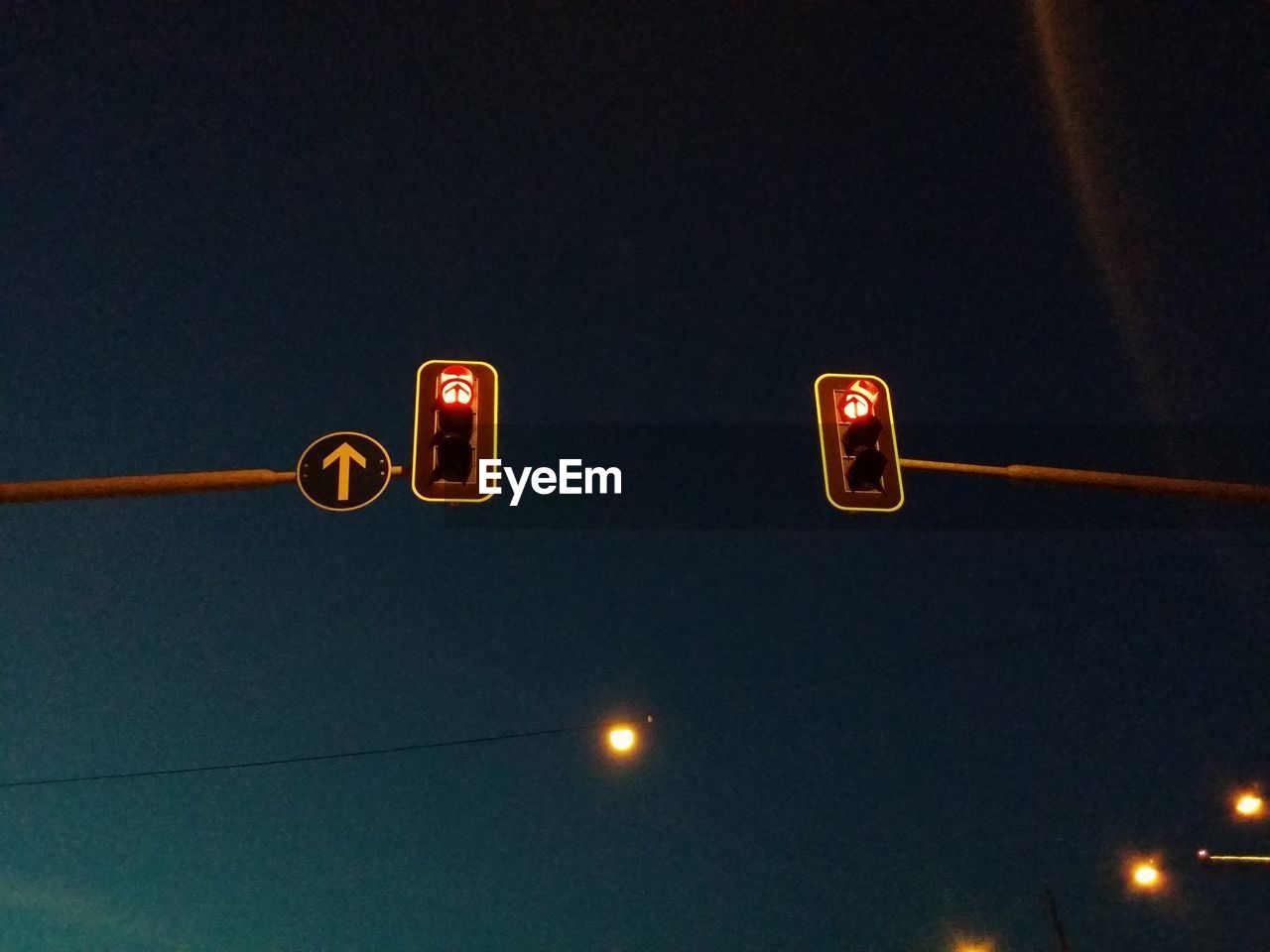 Low angle view of illuminated road signal against sky at night