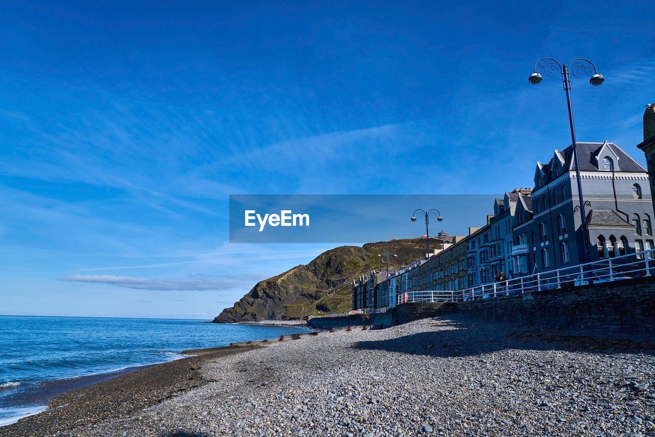 Low angle view of buildings by sea against blue sky