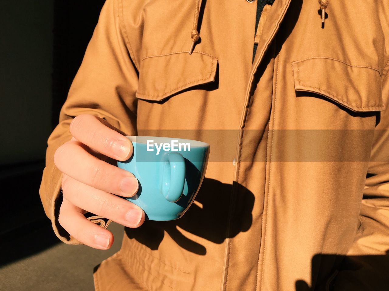 Mid section view of man holding cup of tea