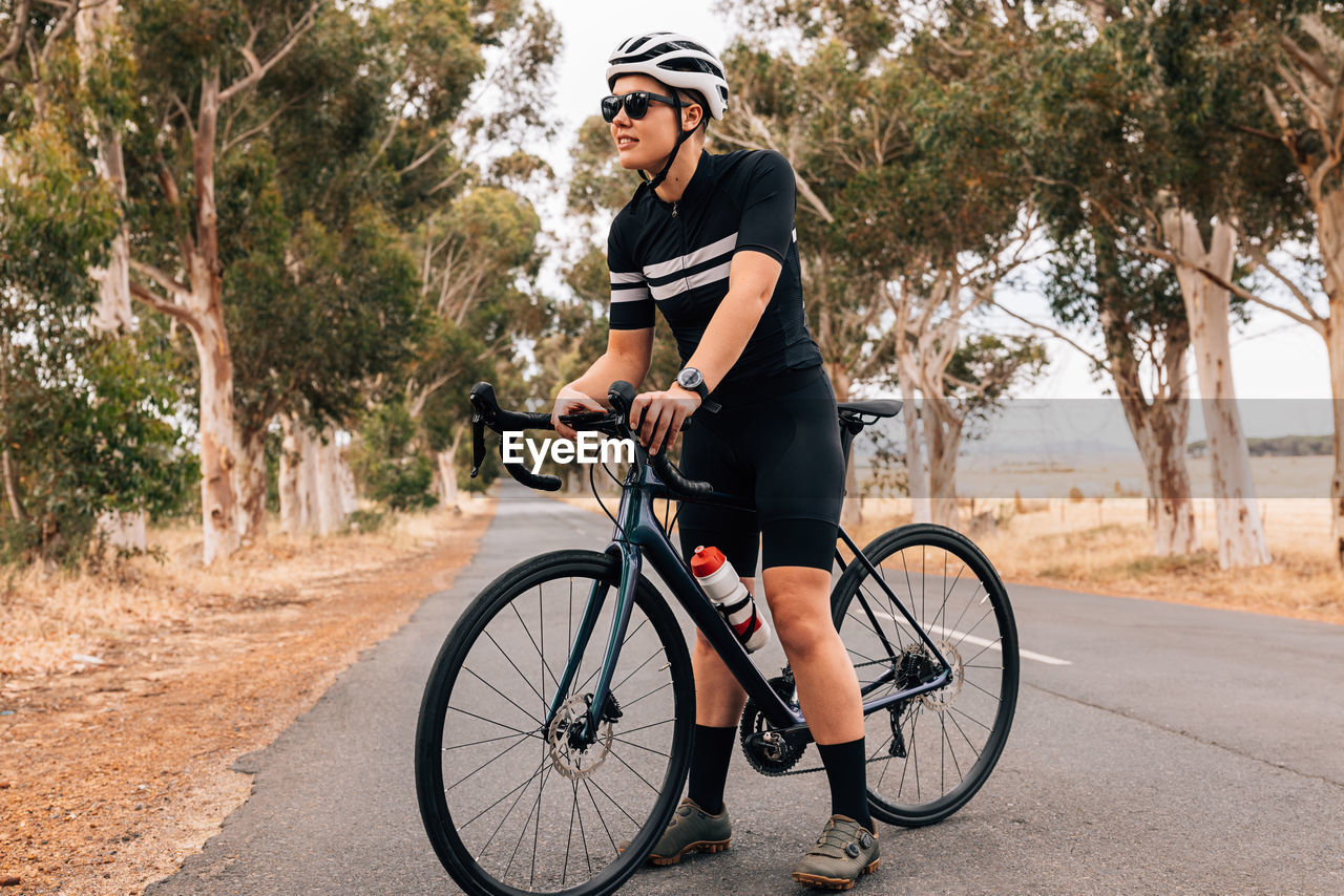 Woman standing with bicycle on road