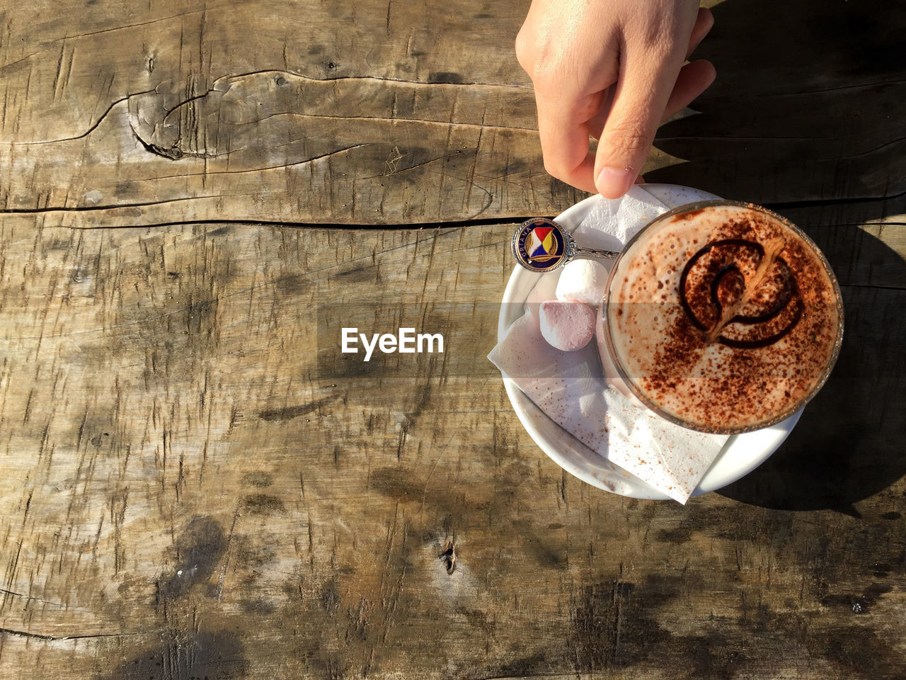 Directly above shot of hand holding coffee and a marshmallow 