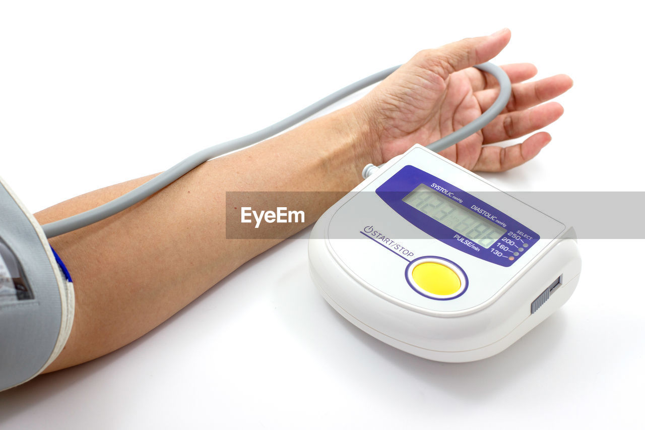 Cropped image of woman measuring blood pressure on white background
