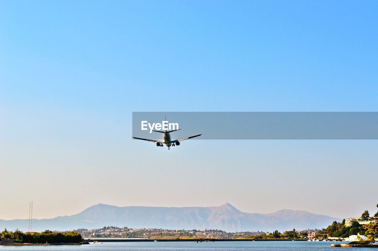 Low angle view of airplane flying and landing on corfu island