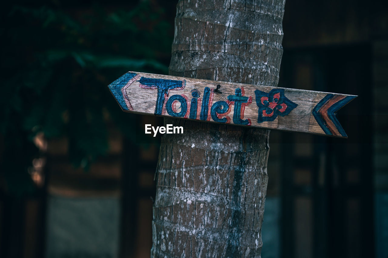 CLOSE-UP OF TEXT ON WOODEN POST AT PARK