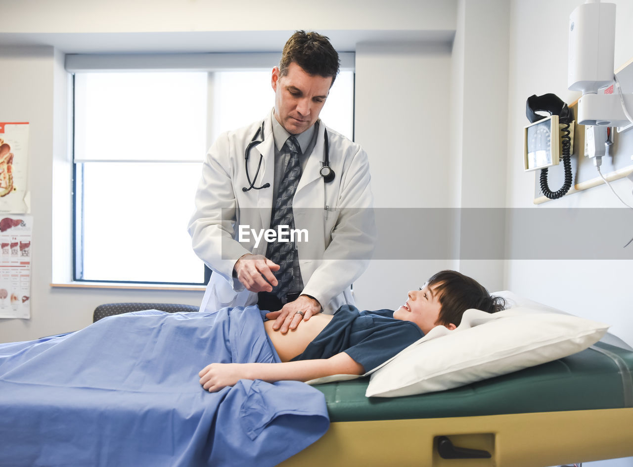 Doctor examining abdomen of child on an exam table of a clinic.