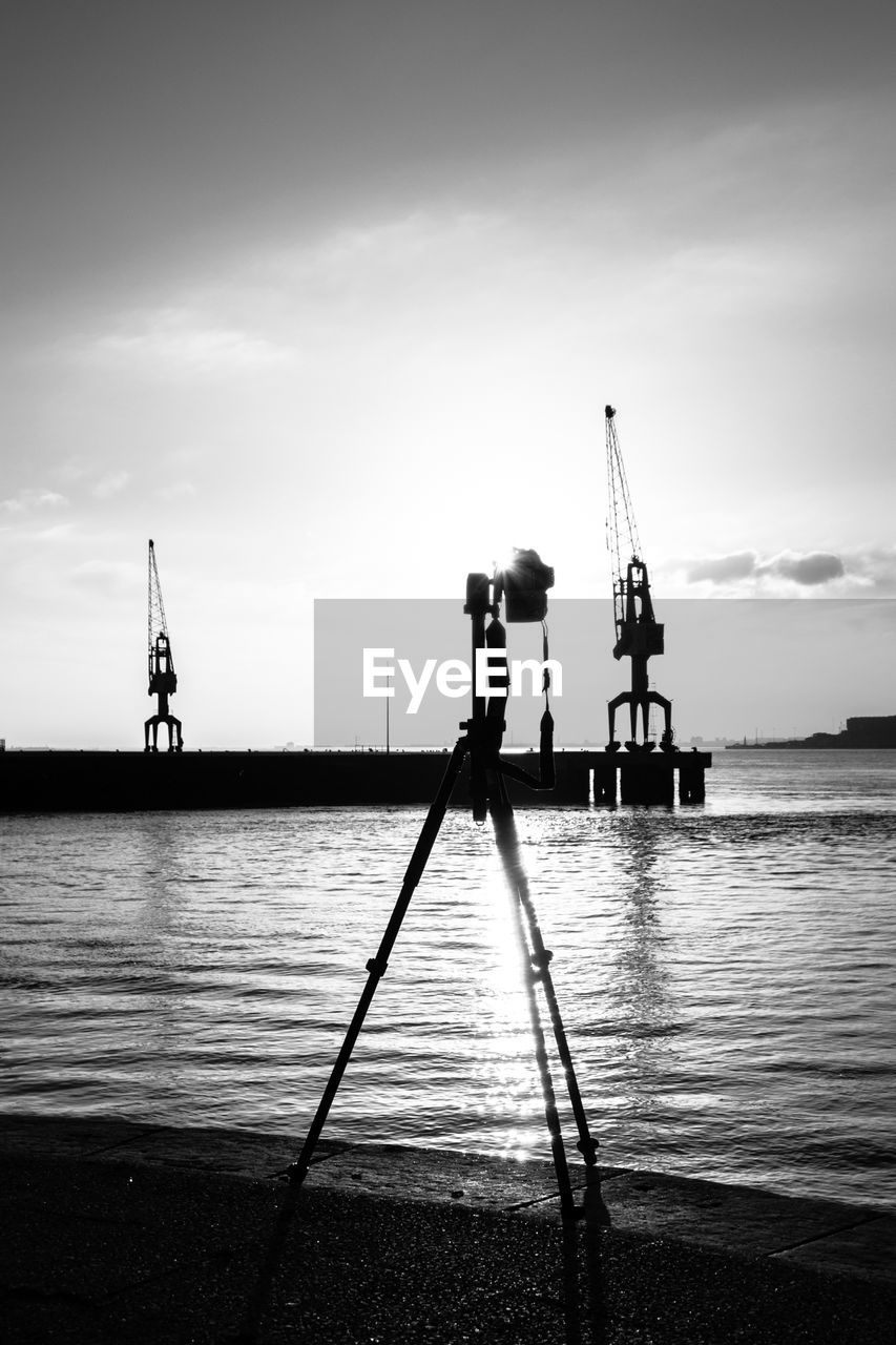 Tripod with cranes in the background on beach