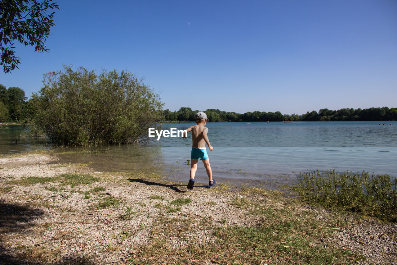 Full length of boy running against lake