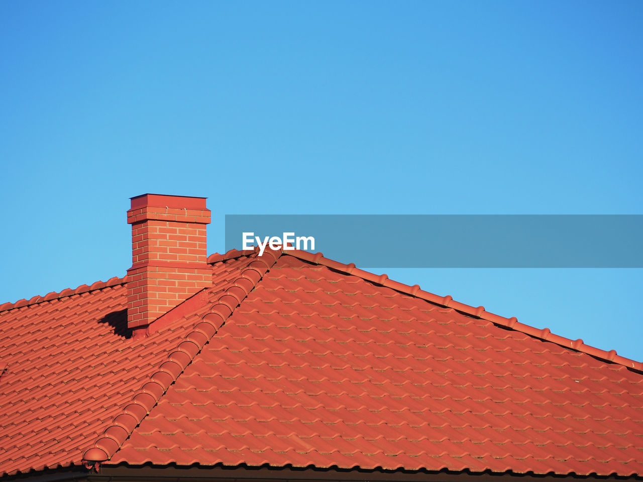 LOW ANGLE VIEW OF HOUSE ROOF AGAINST CLEAR BLUE SKY