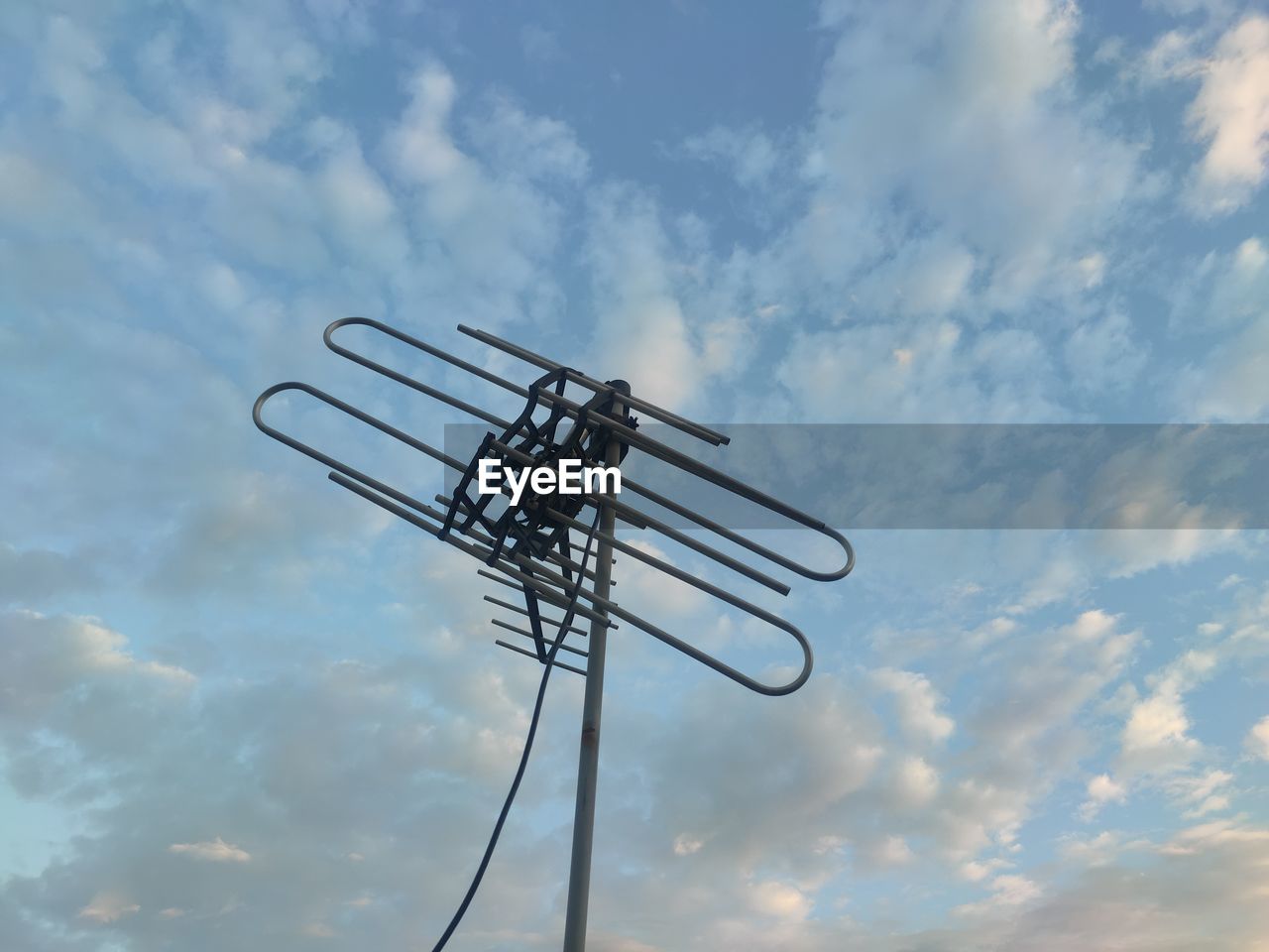 Low angle view of silhouette communications tower against sky