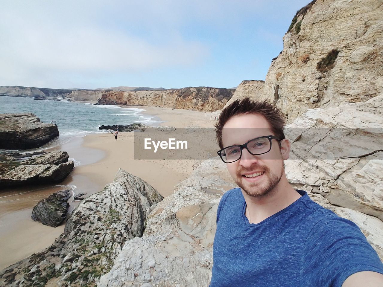 Portrait of man smiling while standing on rocky shore at beach